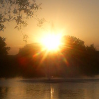 Photo Of Fountain in Pond with Sun Setting Over Trees